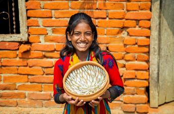 A girl showing nutrient-rich small fish mola (Amblypharyngodon mola), Amtoli, Barguna, Bangladesh. Photo by Md Masudur Rahaman, WorldFish.