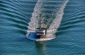 Close up photo of a boat creating a wake in the surrounding water 